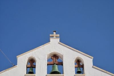 Low angle view of church bell tower against clear blue sky