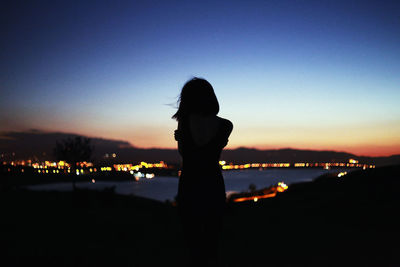 Silhouette woman standing by sea against sky during sunset