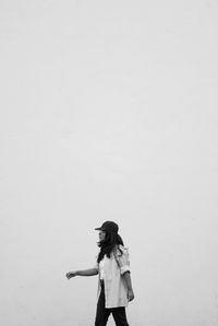 Side view of woman walking against wall