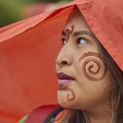 Close-up of thoughtful young woman with face paint wearing orange headscarf