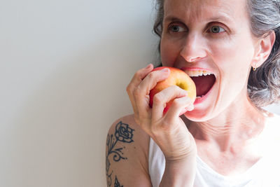 Close-up portrait of young woman eating fruit