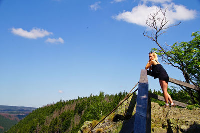 Woman standing at railing against blue sky