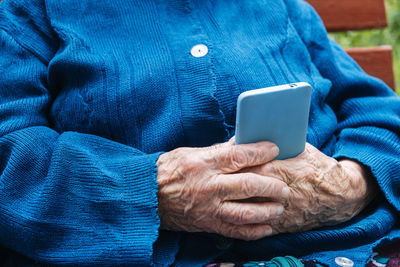 Senior mature woman, grandmother holding phone, using mobile device apps, looking at screen