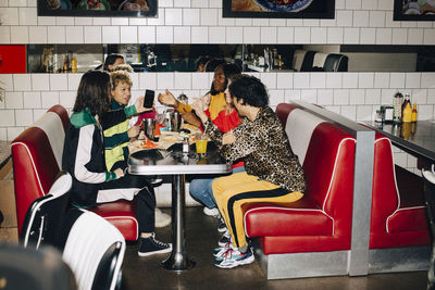 Side view of male and female friends talking at table in cafe