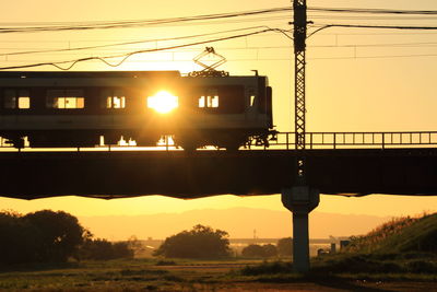Train moving on railway bridge against sky during sunrise