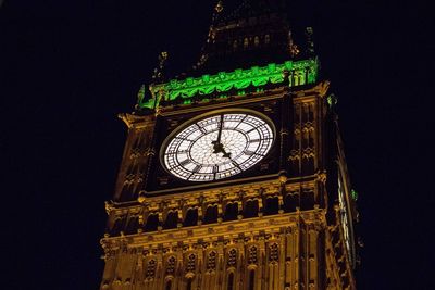 Low angle view of clock tower at night