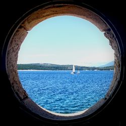 Scenic view of sea against clear blue sky seen through window