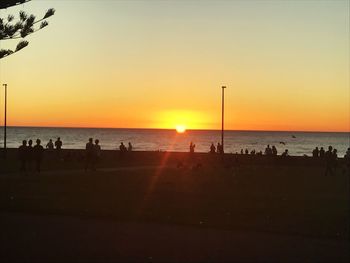 Silhouette people on beach against sky during sunset