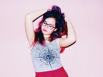 Woman with hand in hair standing against pink background