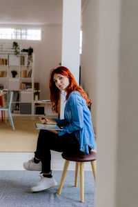 Full length of woman sitting on chair at home