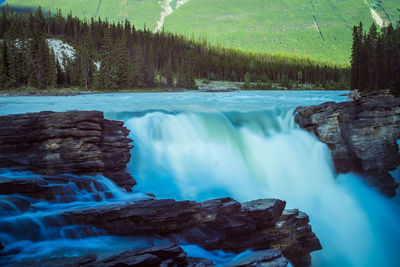 Scenic view of waterfall in forest against sky