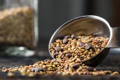 Close-up of various beans falling from measuring spoon on table