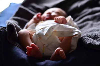 Close-up of new born baby lying on bed at home