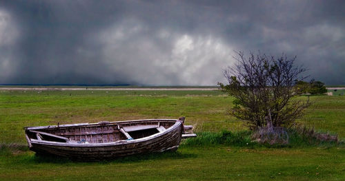 Abandoned boat on field against sky