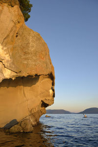 Rock formation in sea against clear sky