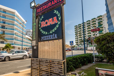 Information sign on road by buildings in city