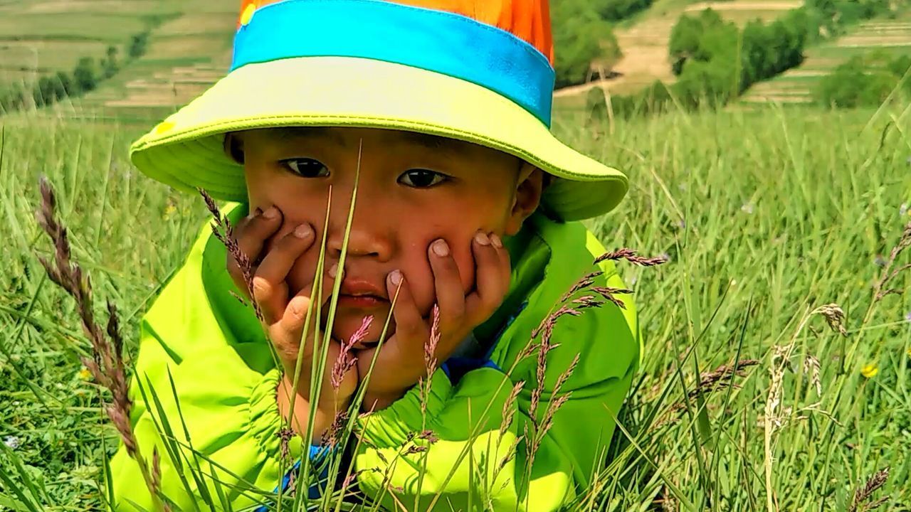 CLOSE-UP PORTRAIT OF HAPPY BOY ON GRASS