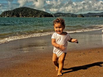 Full length of happy baby walking on shore at beach