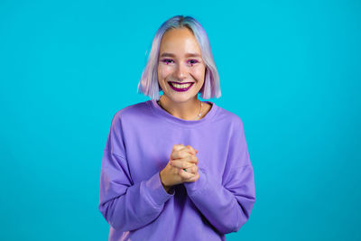 Portrait of a smiling young woman against blue background