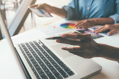 Midsection of man using laptop on table