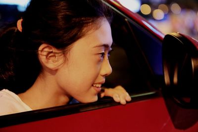 Portrait of young woman looking through car