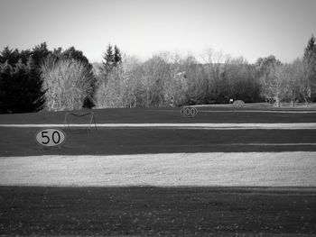 Road by trees on field against sky