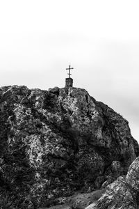 Cross on rock against sky