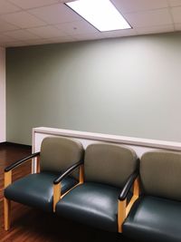 Empty chairs and table against wall