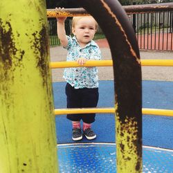 Full length of boy standing by merry go round at playground