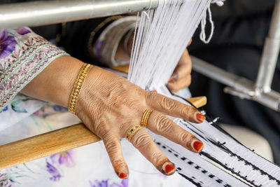 Hands of senior emirati woman using traditional weaving machine