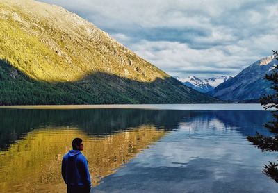 Rear view of man looking at lake against sky