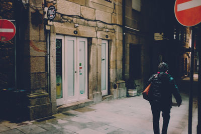 Full length rear view of woman walking on street in city