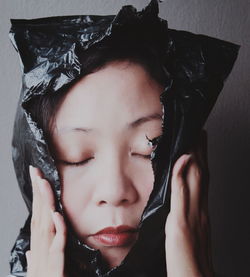 Close-up of woman with eyes closed covered in plastic