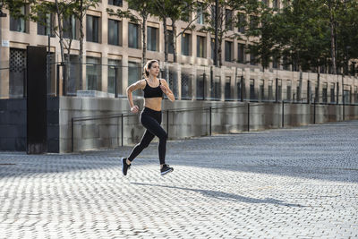 Woman in sportswear jogging on footpath