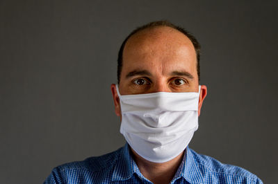 Portrait of man wearing mask against black background