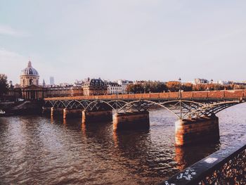 Bridge over river in city against clear sky