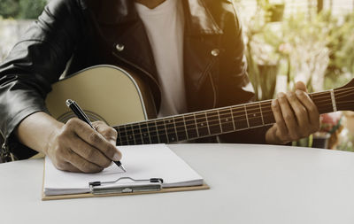 Midsection of man playing guitar on table