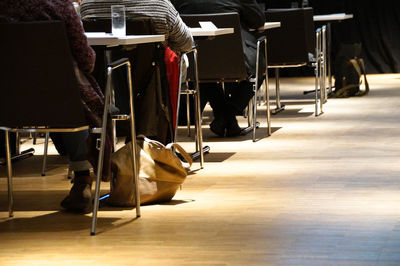 Low section of people sitting on chair over hardwood floor