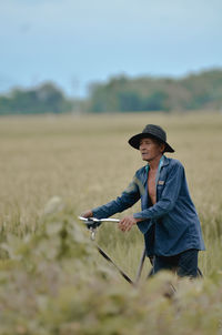 Portrait of young woman using mobile phone while standing on field