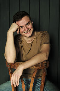 Handsome young man in t-shirt and jeans laughs alone