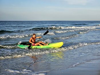 Man kayaking on sea against sky