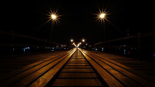 Diminishing perspective of boardwalk against sky at night