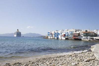 Sea by buildings against clear sky