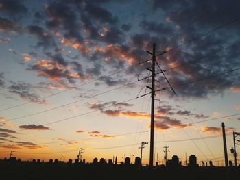 Low angle view of electricity pylon against cloudy sky