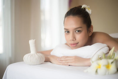 Portrait of smiling young woman lying on massage table in spa