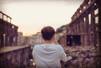 Rear view of man looking at city buildings against sky