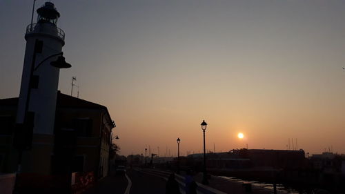 Street amidst buildings against sky during sunset