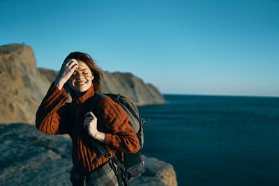 Young woman standing by sea against sky