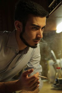 Thoughtful businessman smoking while leaning on kitchen counter