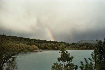 Scenic view of rainbow over lake against sky